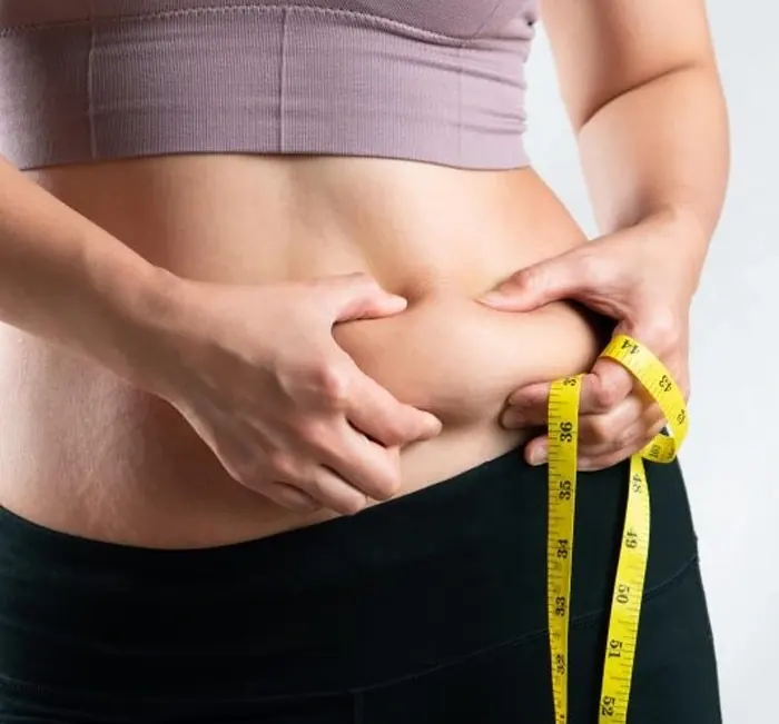A person measuring their waist with a tape measure