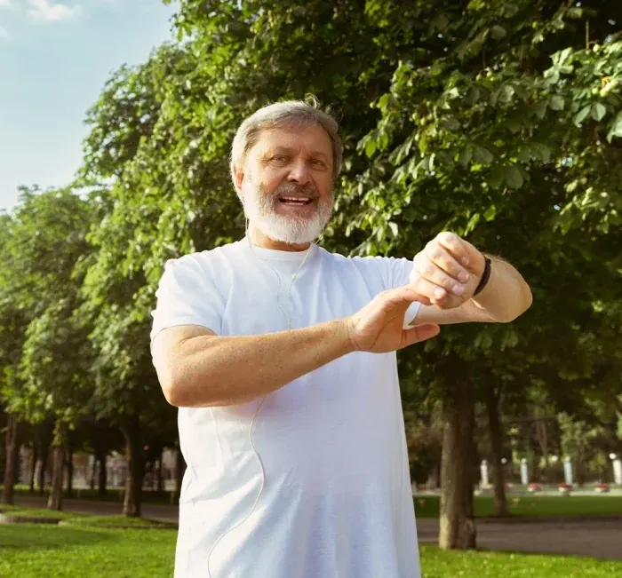 An older man in a park checking his watch